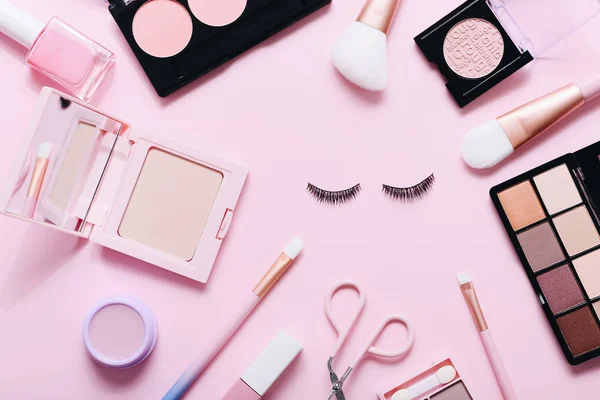 Плоская композиция с продуктами для декоративного макияжа на розовом фоне — стоковое фото