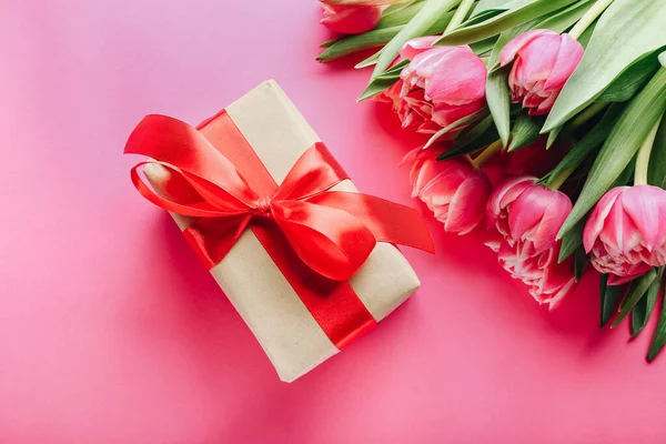 Подарочная коробка и букет красивых тюльпанов на розовом фоне — стоковое фото