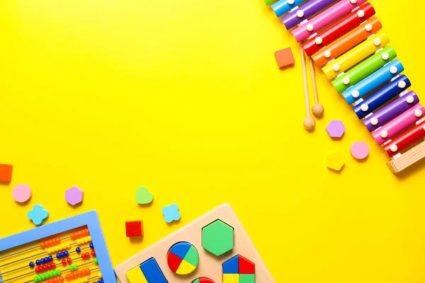 Kleurrijke kinderen speelgoed op gele achtergrond. Bovenaanzicht, vlak lay. — Stockfoto