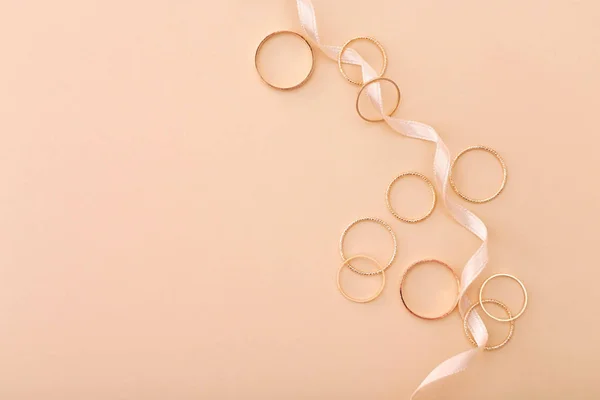 Muchos anillos de oro y cinta sobre fondo beige — Foto de Stock