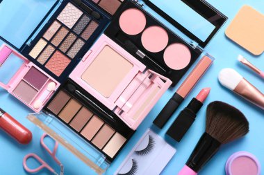 Set of professional decorative cosmetics, makeup tools and accessory on blue background.