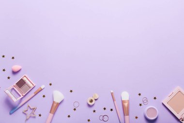 Set of professional decorative cosmetics, makeup tools and accessory on lilac colored background. Beauty, fashion and shopping concept. Flat lay composition, top view