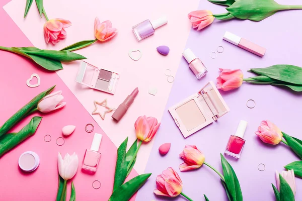 Kompozycja płaska z kosmetykami do makijażu i różowymi tulipanami na różowym tle — Zdjęcie stockowe