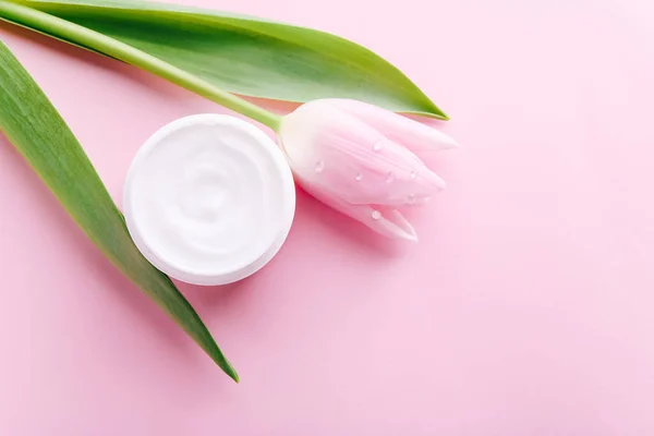 Tarro de crema y tulipán rosa sobre fondo rosa, vista superior. Productos cosméticos profesionales — Foto de Stock