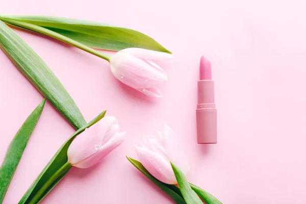 Lápiz labial rosa y hermosos tulipanes sobre fondo rosa pastel. Vacaciones para niñas — Foto de Stock