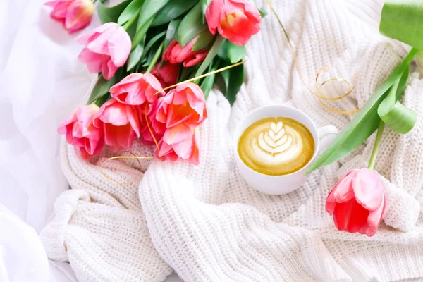 Delicious coffee and a bouquet of pink tulips in a bed