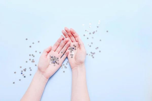 Mãos com estrelas cintilantes decorações sobre fundo azul. Imagem atmosférica elegante. Feliz aniversário conceito. Decoração de férias. Magia nas mãos. Natal. — Fotografia de Stock