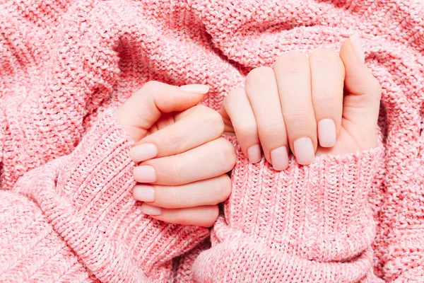 Hermosa manicura de mujer sobre fondo suéter de punto rosa. Tendencia minimalista de manicura. Vista superior, cama plana. Copia espacio para tu texto . — Foto de Stock