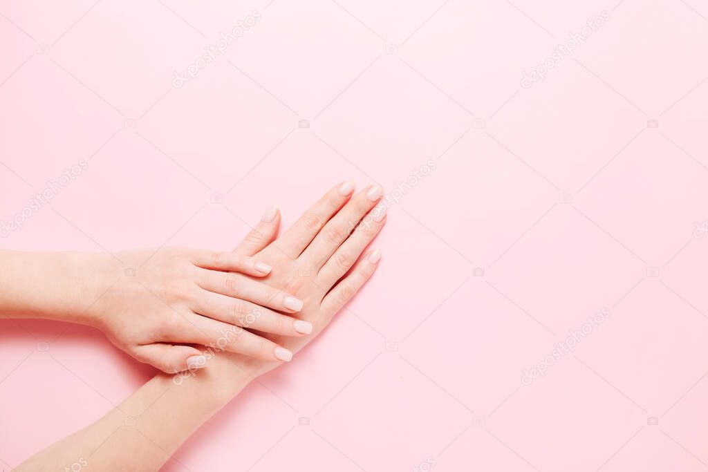 Womans hands with beautiful manicure on pink background. Hands spa concept