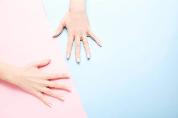 Elegante manicura femenina de moda. Hermosas manos de mujeres jóvenes sobre fondo rosa y azul . — Foto de Stock