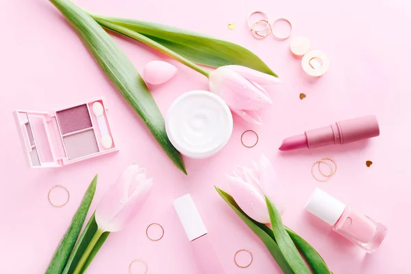 Kompozycja płaska z kosmetykami do makijażu i różowymi tulipanami na różowym tle — Zdjęcie stockowe