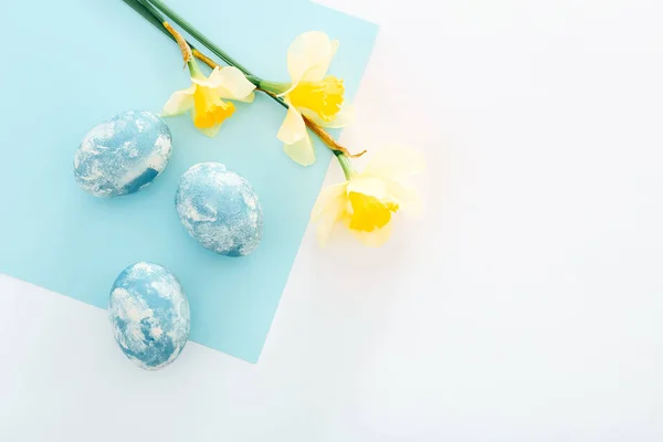 Happy Easter background. Easter eggs with spring flowers on white background, top view