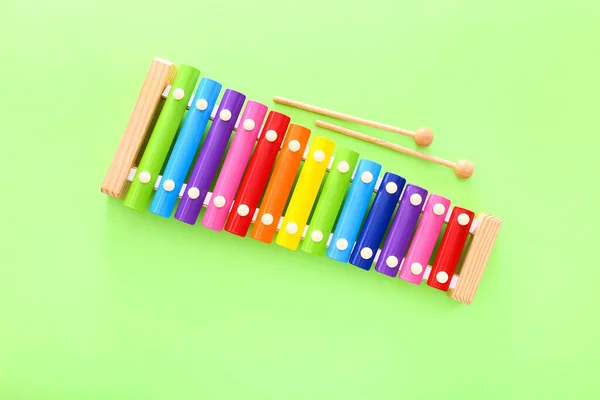 Xylophone jouet en bois de couleur arc-en-ciel avec deux bâtons sur fond vert. Vue du dessus — Photo