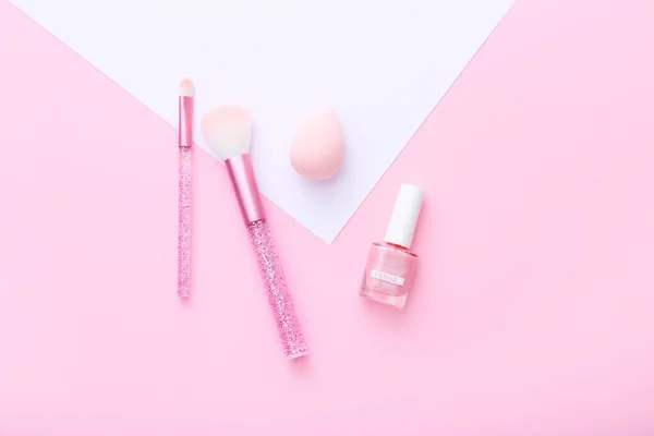 Herramientas femeninas y accesorios de maquillaje sobre fondo rosa y blanco . — Foto de Stock