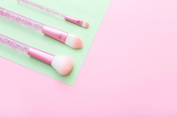 Conjunto de pinceles de maquillaje sobre fondo compuesto de color rosa y verde . — Foto de Stock