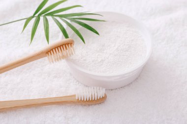 Tahta diş fırçaları ve beyaz havlu üzerindeki diş pudrası. Sıfır atık