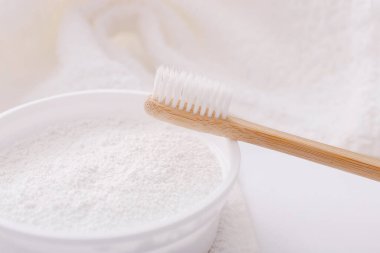 Tahta diş fırçası ve beyaz havlunun üzerindeki diş pudrası. Sıfır atık