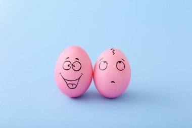 Mavi arka planda yüzü olan komik pembe yumurtalar.