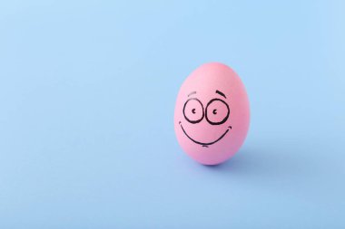 Mavi arka planda yüzü olan komik pembe yumurta.