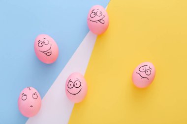 Renkli arka planda yüzü olan komik pembe yumurtalar.