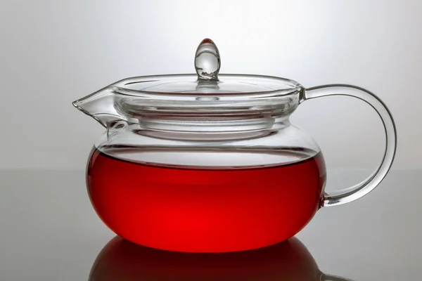 Théière en verre transparent avec thé sur fond gris — Photo