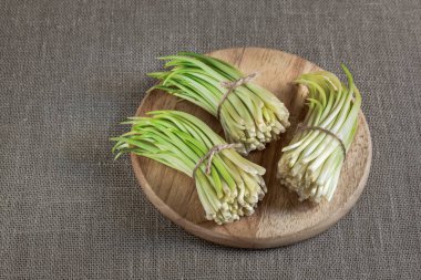 Yaban sarımsağı ahşap bir tepside, çuval bezi arka planda.