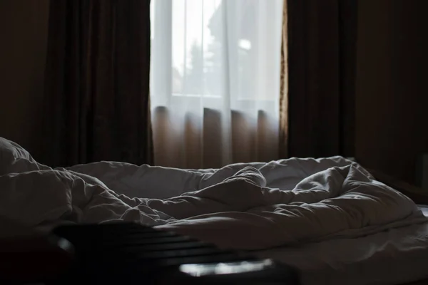 Bir otel odasında yapılmamış yatak. Sabahın erken saatlerinde, pencerelerden gelen ışık. Bir otel odasında yapılmamış yatak. Sabah erkenden, gölge..