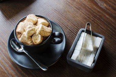Tarçınlı sıcak çikolata ve ahşap arka planda marşmelov.