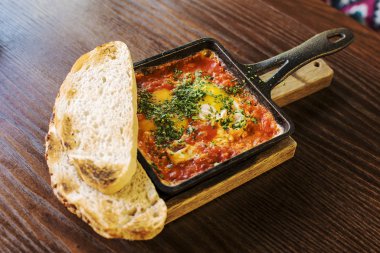 Shakshuka ahşap arka planda dökme demir tavada.