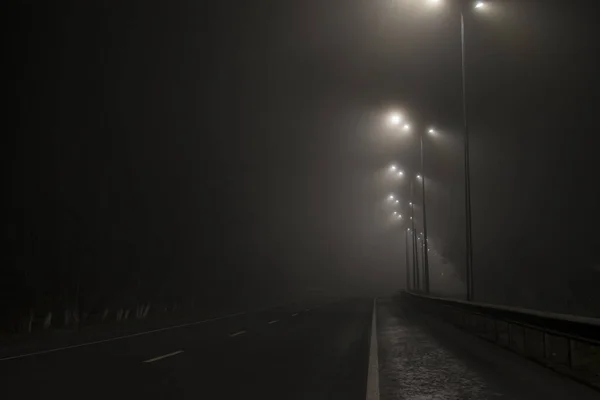 Empty road fog at night. Along the road lights are on. — Stock Photo, Image