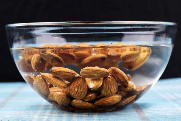 Almonds kept in a glass bowl containing water.