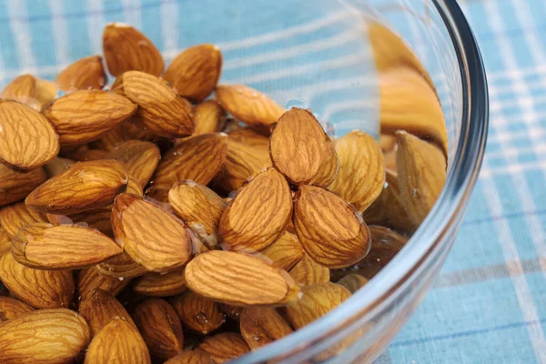 Almonds kept in a glass bowl containing water.