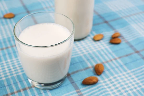 Mandel mjölk i glas med mandel i skål, på färg trä bakgrund — Stockfoto