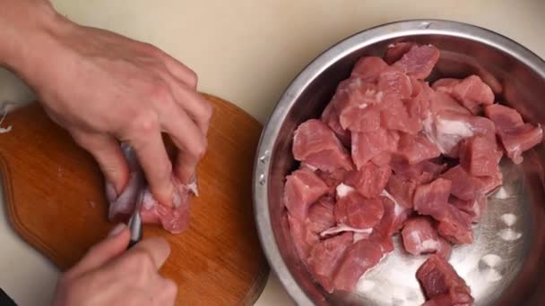 Vrouwelijke handen van een kok met een keukenmes scheiden de pees van het varkensvlees — Stockvideo