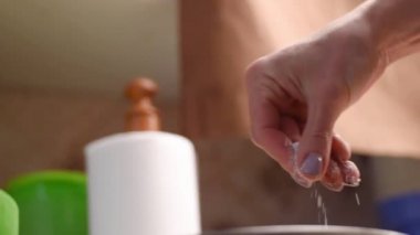 Bir aşçının eli bir tabak balığa, pilav ve salataya yavaş çekimde otlar serper..