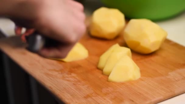 Hand in hand met een mes dat verse groenten snijdt. Vrouw snijden aardappelen op een witte snijplank closeup. — Stockvideo