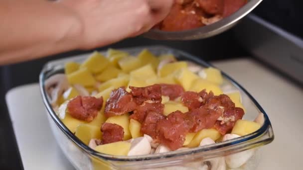 Mãos femininas adicionam carne crua às batatas cruas . — Vídeo de Stock