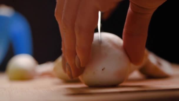 Mani femminili con bella manicure sulle dita tagliano funghi con un coltello da cucina su un tagliere di plastica blu, primo piano. Champignon. donna che prepara la cena a casa — Video Stock