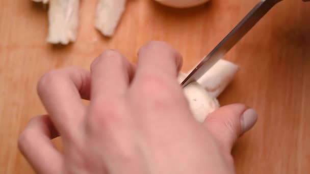 Manos femeninas con hermosa manicura en los dedos cortan setas con un cuchillo de cocina en una tabla de cortar de plástico azul, de cerca. Champiñón. mujer preparando la cena en casa — Vídeos de Stock