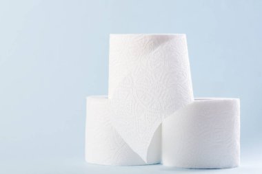 Mavi arka planda beyaz tuvalet kağıdı yuvarlanıyor. Hijyen kavramı.