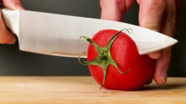 Domates kesimi yakın plan. Şef vişneli domatesi dilimliyor. Salata için sebze kes. Sağlıklı yiyecekler. Yakın plan..