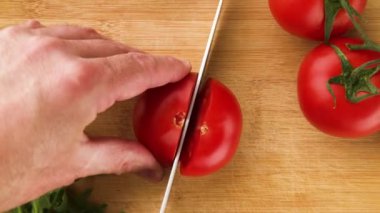 Domates kesimi yakın plan. Şef vişneli domatesi dilimliyor. Salata için sebze kes. Sağlıklı yiyecekler. Üst görünüm.
