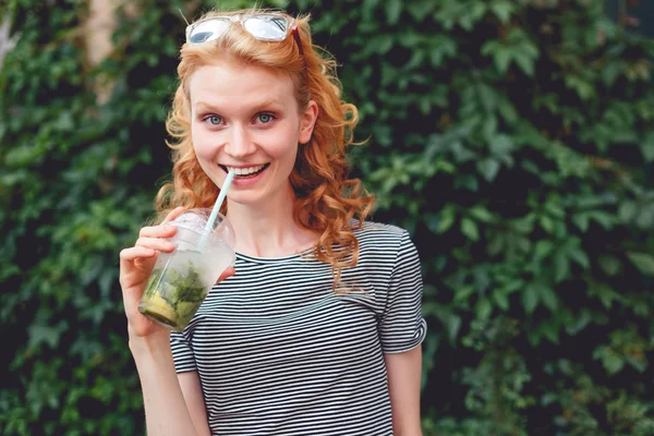 Ginger dívka s úsměvem vedle zelené bush, Foto laděných — Stock fotografie