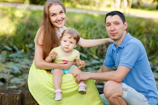 Jeune famille dans le parc au milieu des buissons — Photo