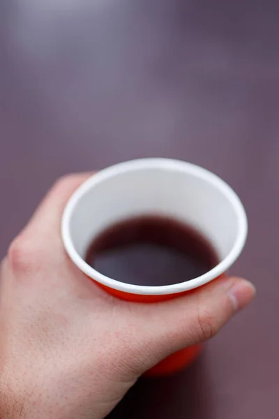 Obraz z mans dłoń trzymająca czerwony papier szkło z herbatą — Zdjęcie stockowe