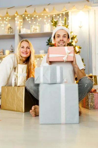 Afbeelding van man en vrouw in kerst pet met gave in vak — Stockfoto