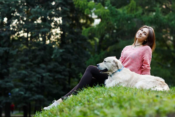 Foto van onderen van vrouw zitten met de hond op groen gazon — Stockfoto