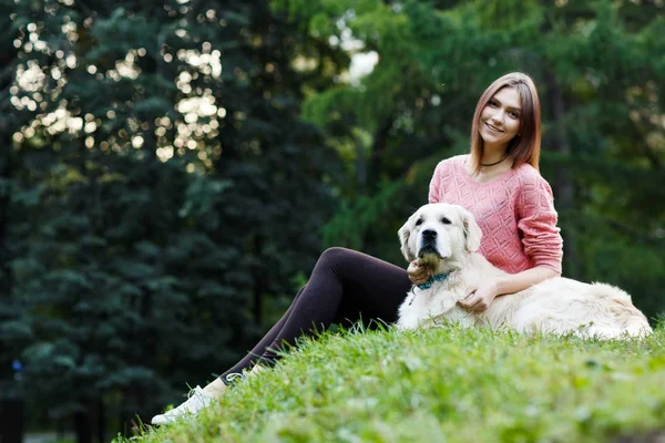 Imagem de baixo da morena sentada com o cão no gramado verde — Fotografia de Stock