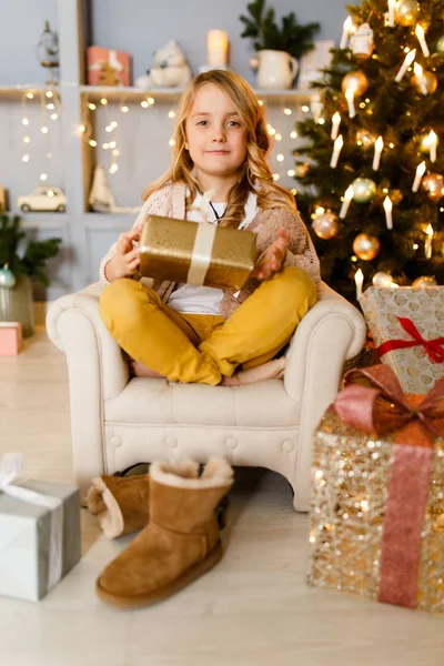 Imagen de niña sentada en silla sobre fondo de decoraciones navideñas — Foto de Stock