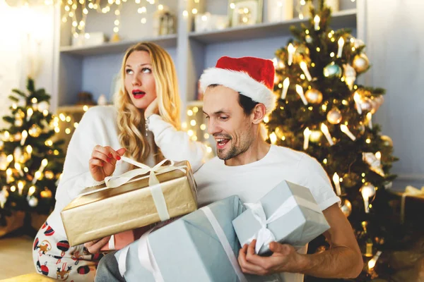 Foto de pareja alegre en gorra de Santa con regalo en caja — Foto de Stock